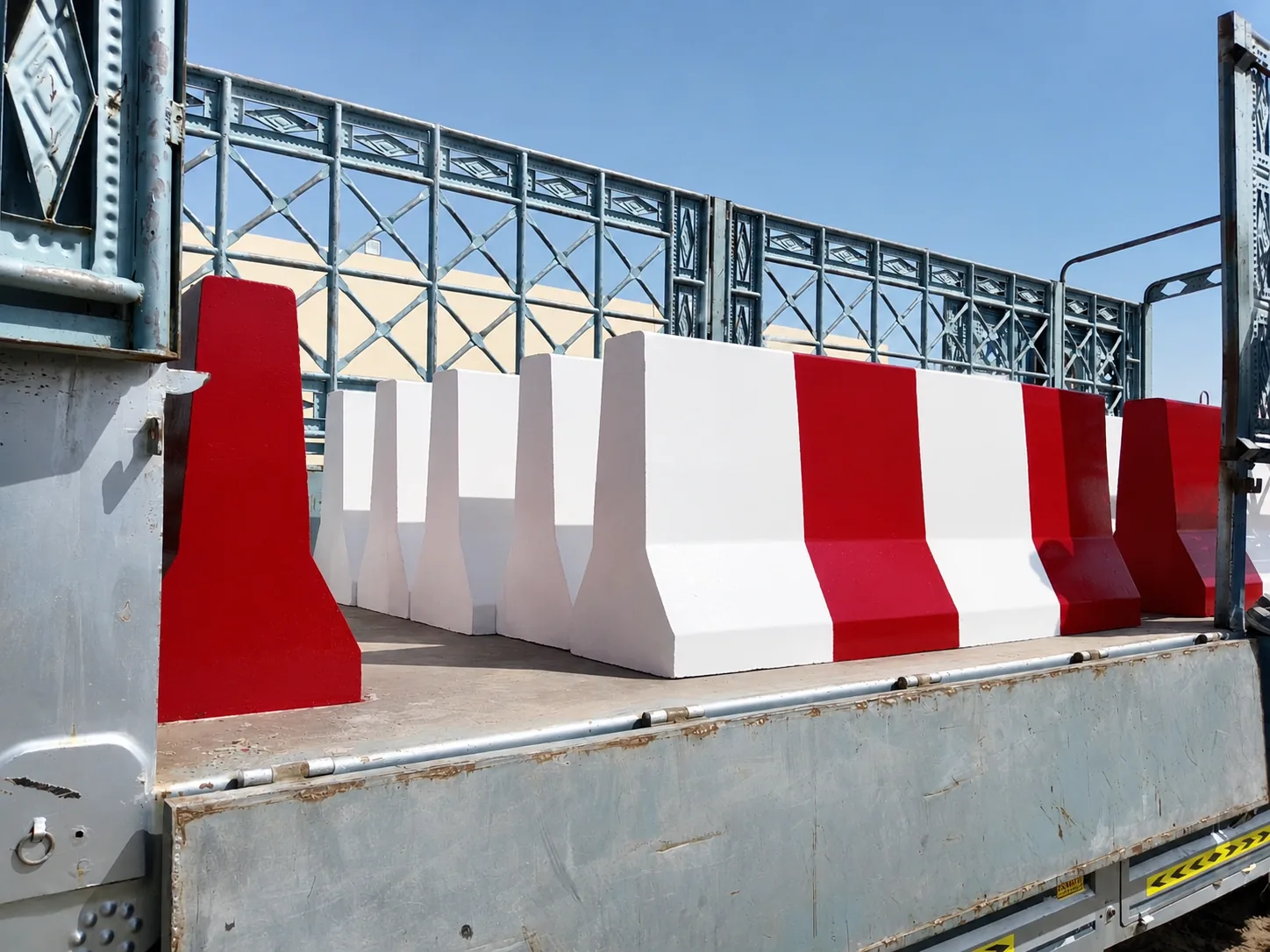 Red and white precast concrete barriers loaded on a flatbed trailer for UAE delivery