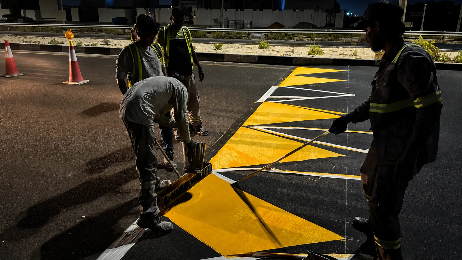 Road-marking crew applying yellow and white channelisation markings at night in the UAE