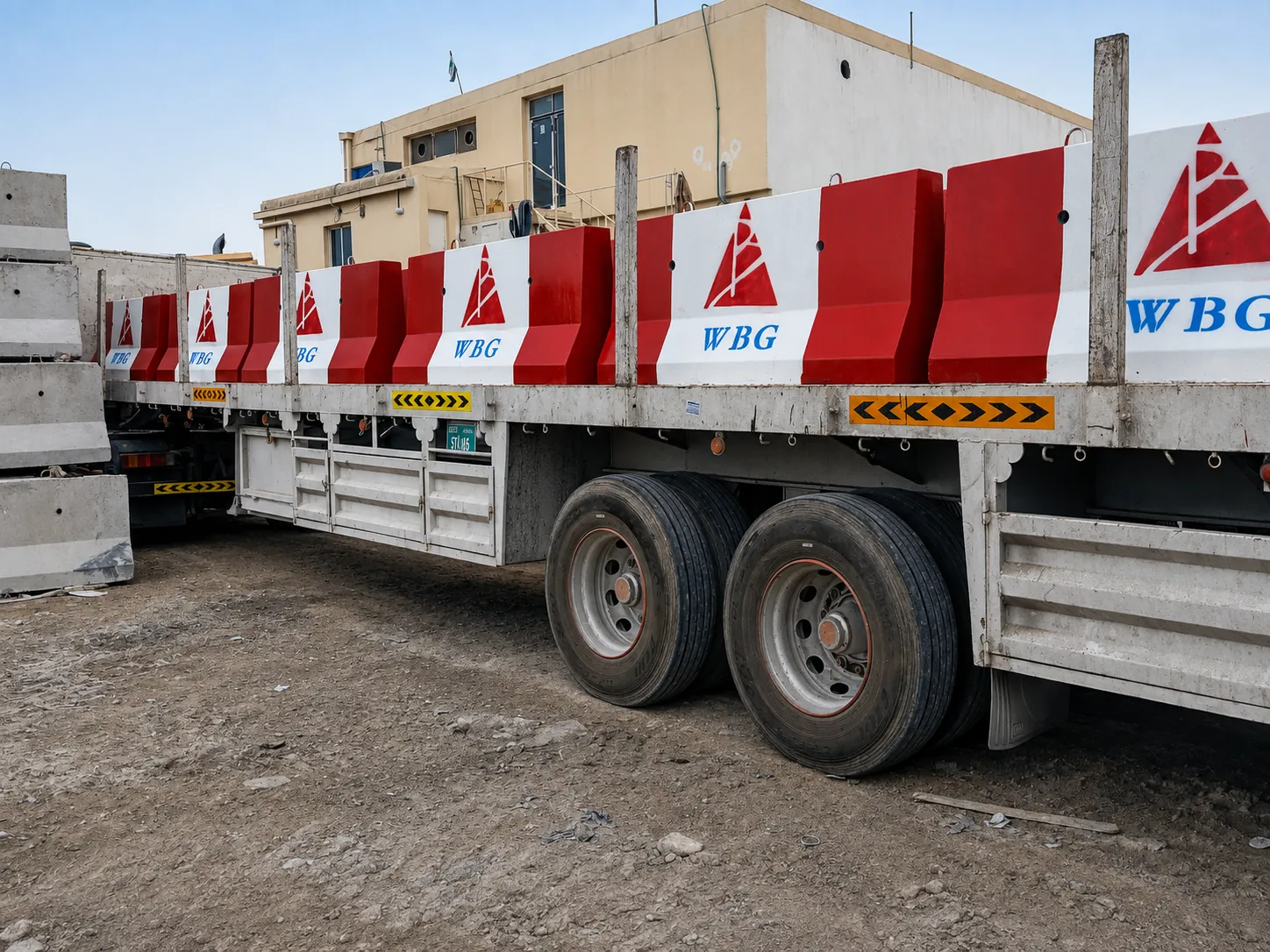 Flatbed truck carrying red and white precast concrete road barriers for UAE project delivery