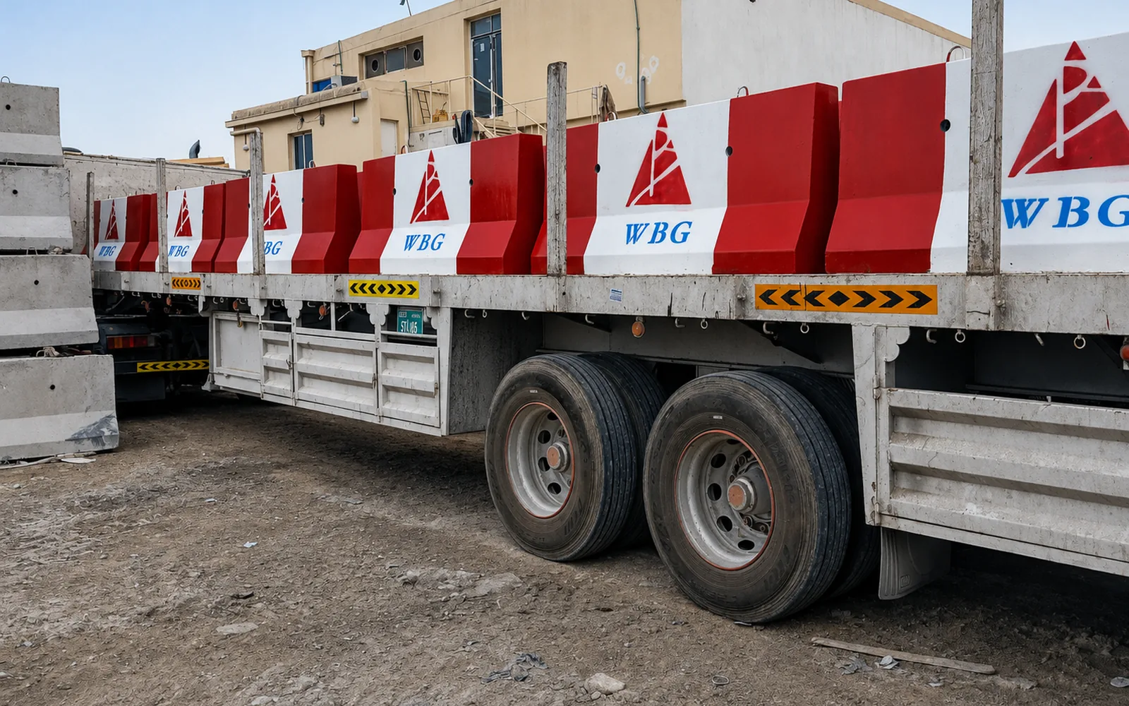 Flatbed trailer carrying red and white precast concrete barriers for project delivery in the UAE