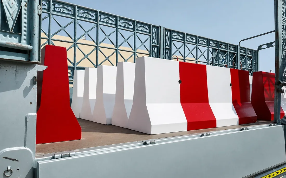 Red and white concrete barrier delivery in the UAE Red and white concrete barriers loaded on a truck for UAE delivery