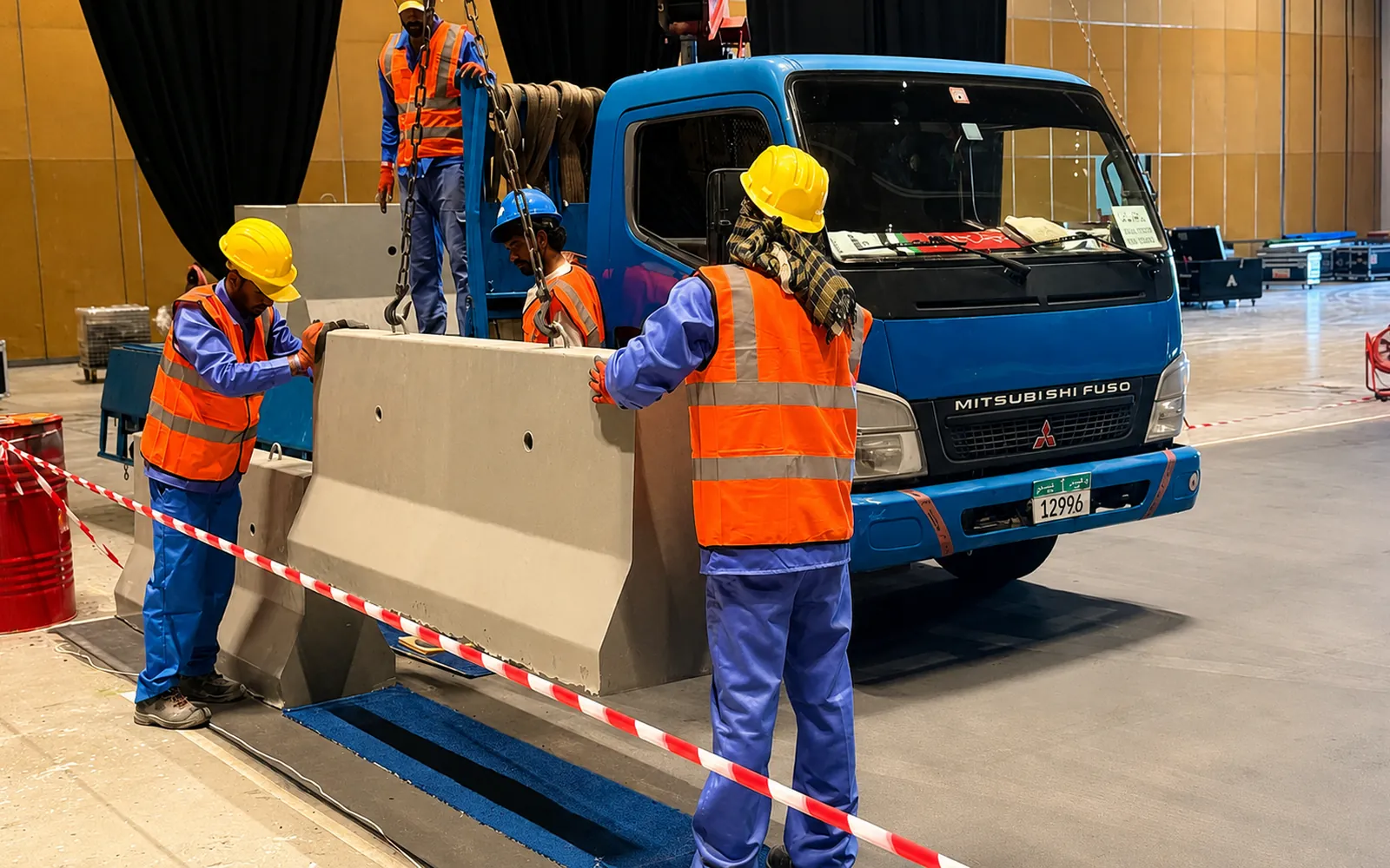 Installation crew positioning a precast concrete barrier with a truck-mounted crane in the UAE