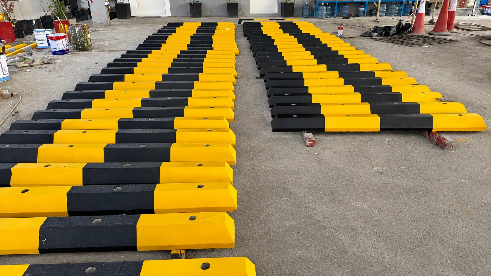 Bulk yellow and black precast concrete wheel stoppers arranged in a UAE production yard