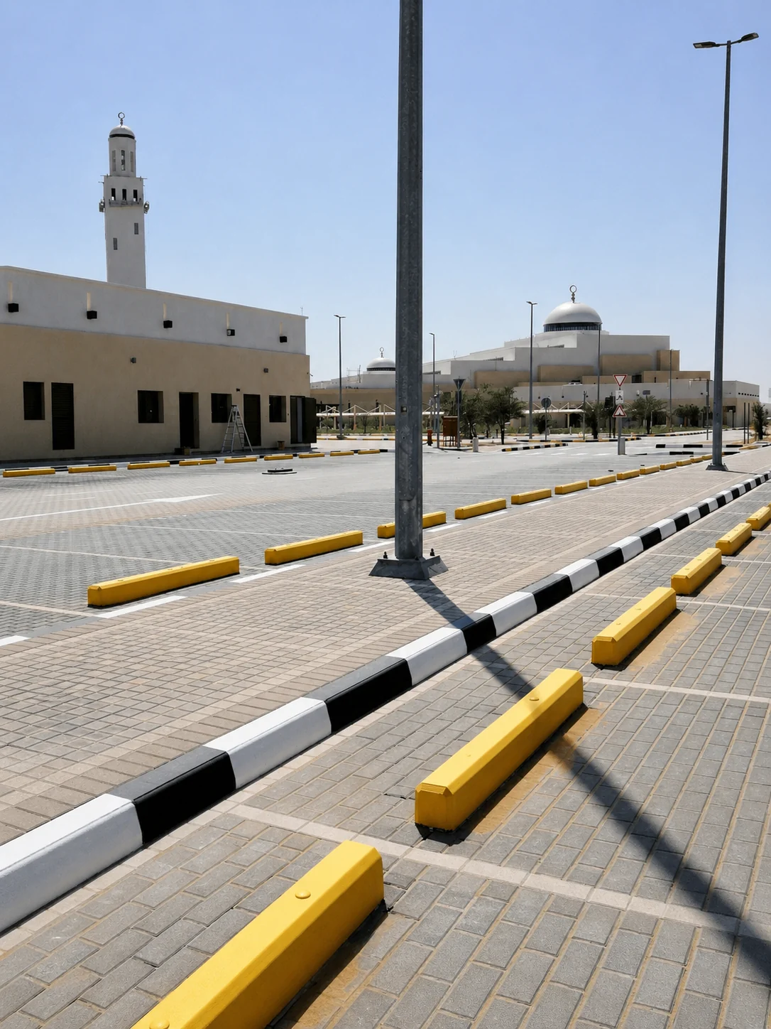 Yellow precast concrete wheel stoppers installed in a paved UAE parking area