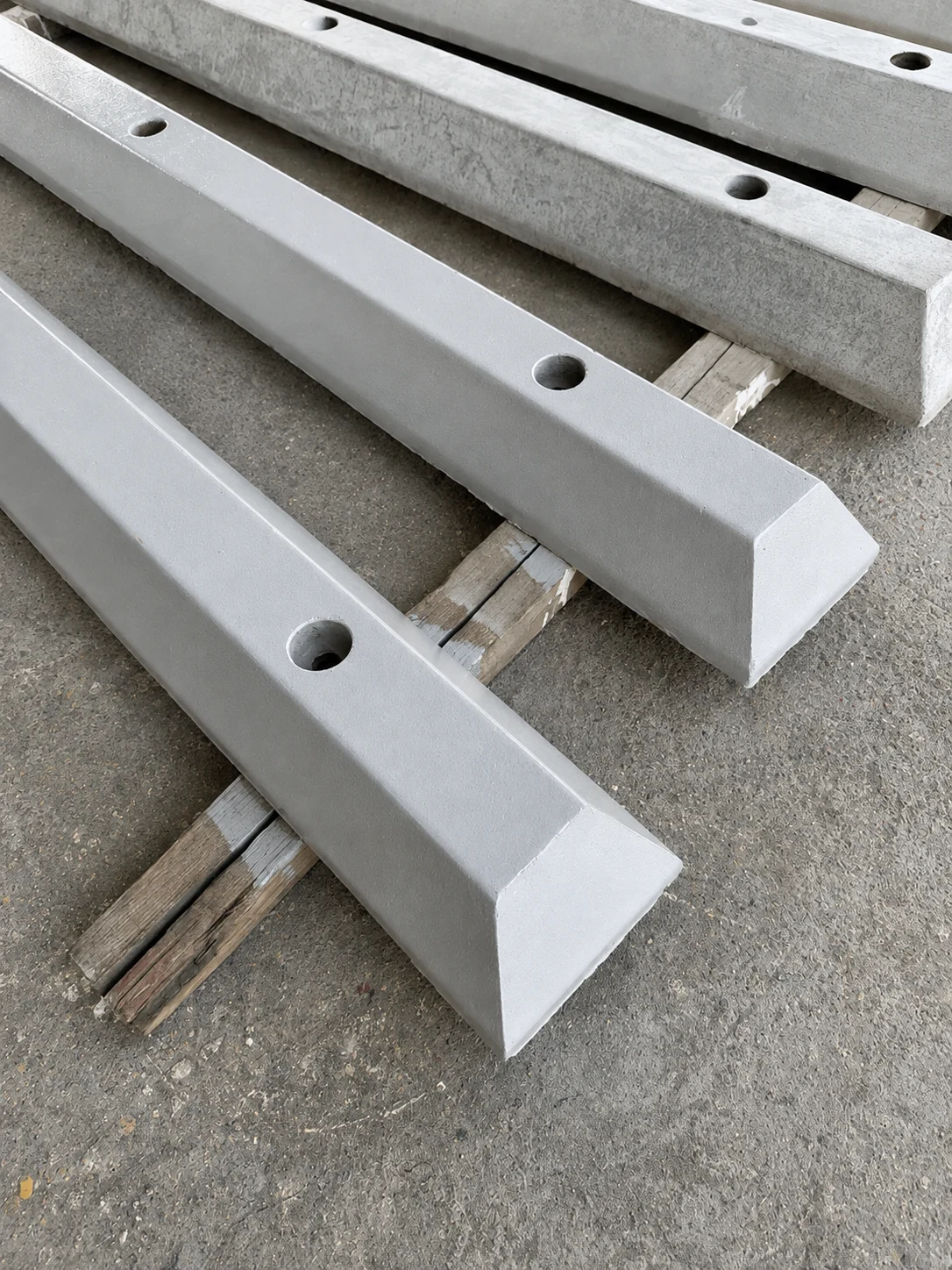Unpainted precast concrete wheel stoppers with fixing holes in a UAE production yard