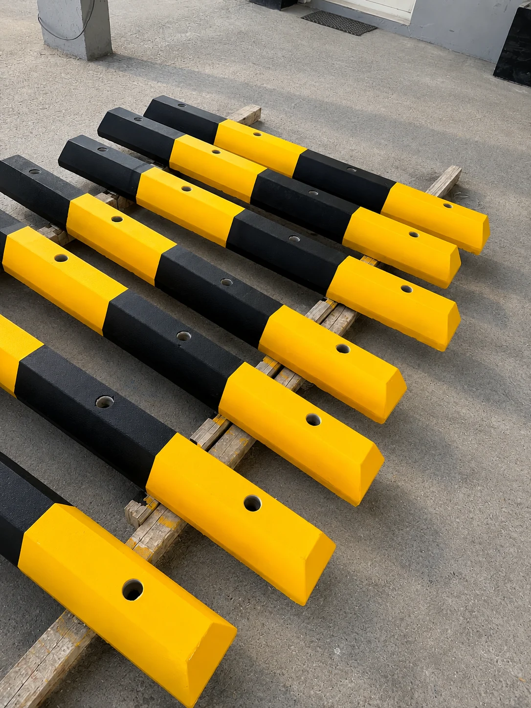 Painted yellow and black precast concrete wheel stoppers arranged for UAE project supply
