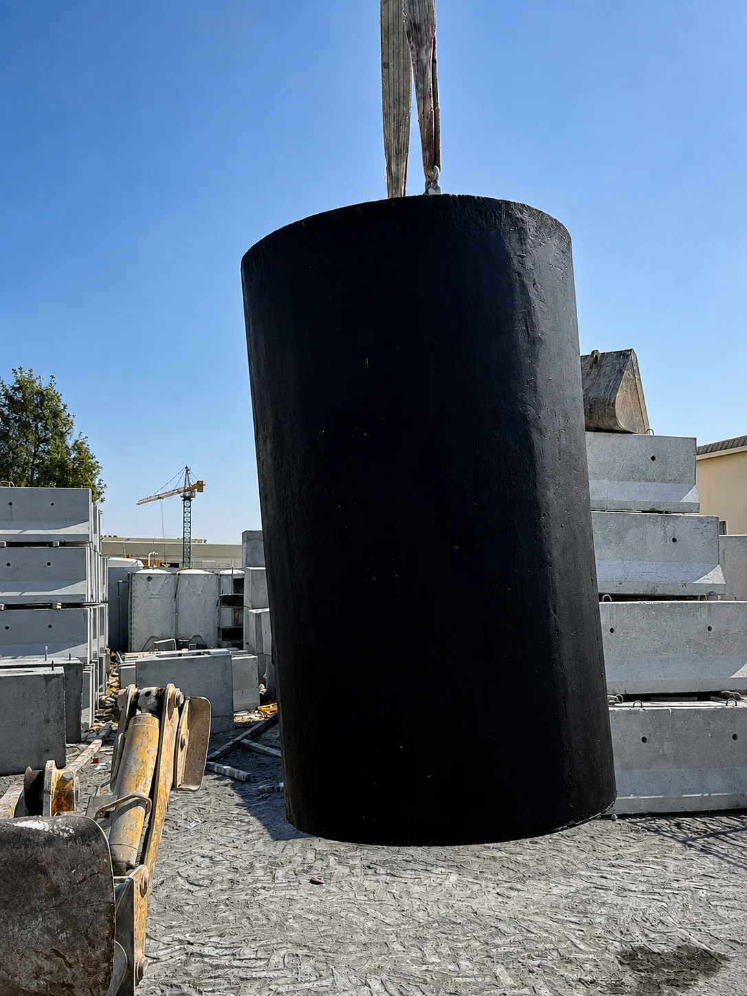 Protective-coated cylindrical precast concrete foundation being handled in a UAE precast yard